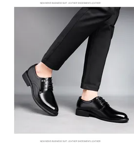Un homme portant des chaussures de ville en cuir noir brillant sur un fond gris
