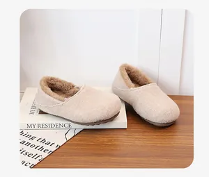 Close-up of beige fuzzy slippers with warm brown plush lining on a wooden desk
