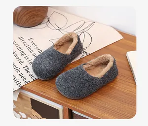 Close-up detail of grey felt slippers with warm plush lining on wooden surface