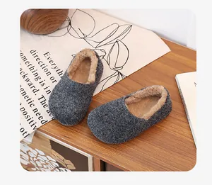 Detailed view of grey fuzzy loafers with warm faux fur lining on a wooden desk