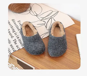 Cozy grey fuzzy-lined winter mule slippers with soft soles shown on a wooden table