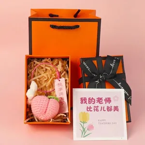 Detailed view of a handmade crochet peach keychain in an elegant orange gift box set