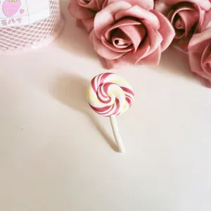 Detailed view of a cute pink and white swirl lollipop brooch made of polymer clay. (81 chars)