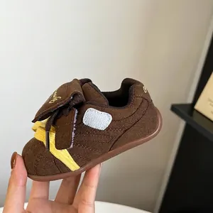 Vista detallada de zapatillas de bebé de gamuza marrón con cordones amarillos y velcro
