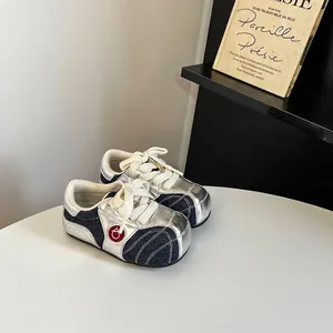 Close-up of children's silver and denim patchwork German Army Trainer style sneakers.