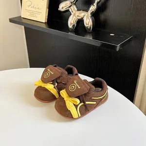 Vista detallada de zapatillas marrones para bebés con detalles de lazos amarillos vivos