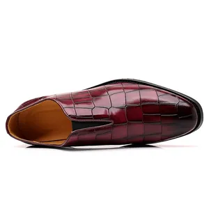 Detail von weinrotem Herren-Business-Schuh mit Krokodilmuster und spitzer Kappe