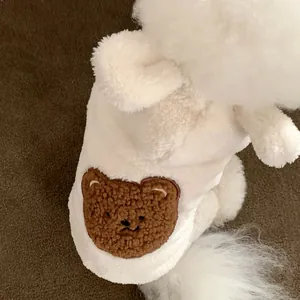 Close-up of a fluffy white pet vest featuring a cute brown bear embroidery detail