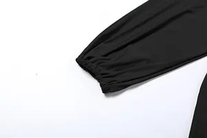Macro view showing the elasticized cuff detail of a stylish black long-sleeved jumpsuit