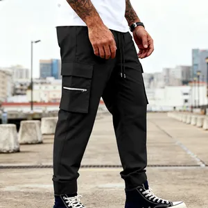 Vista detallada de los pantalones cargo negros para hombre con bolsillo con cremallera y puños.