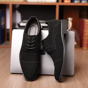 Makroansicht schwarzer Business-Schuhe aus Wildleder mit Brogue-Muster am Tisch.