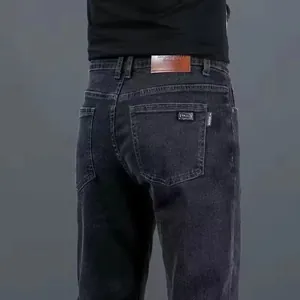 Dettaglio posteriore di jeans elasticizzati neri slim fit da uomo con toppa in pelle