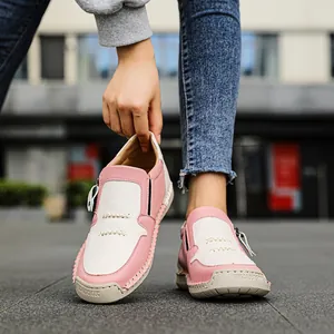 Primo piano di mocassini casual da donna in pelle rosa e bianca in ambiente urbano