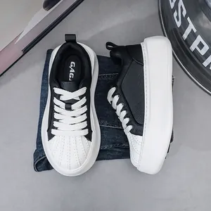 Close-up detail of black and white leather shell-toe sneakers with thick platform soles.