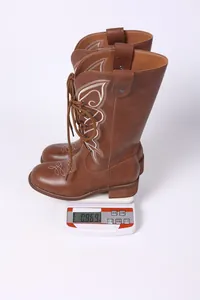 Close-up of brown embroidered boots on a digital scale showing weight of 0.869 kg