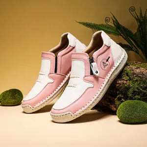 Dettaglio stivaletti in pelle rosa e bianca da donna con cerniera laterale e suola in gomma.