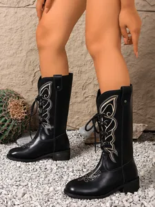Detailed side view of black mid-calf boots with white butterfly embroidery patterns