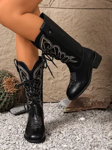 Detail showing black western style boots with intricate white embroidery and lace-up front.