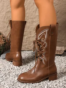 Close-up detail of stylish brown western boots featuring elegant white embroidery
