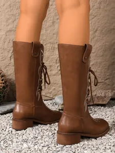 Detailed macro view of stylish brown knee-high boots with elegant white embroidery