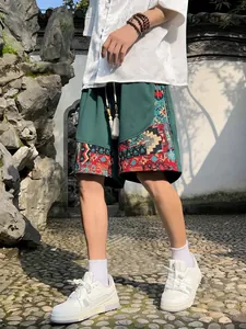 Detail showing ethnic embroidered patterns on green linen casual shorts.