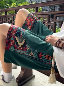 Detailed view of ethnic pattern on men's dark green breathable linen shorts in lifestyle setting.