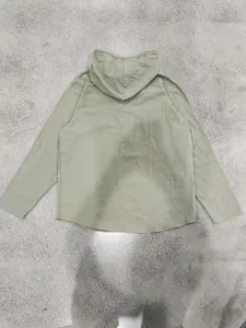 Back view of a loose sage green linen hooded long sleeve shirt for men on grey floor