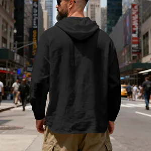 Back view of a men's loose black linen hooded henley shirt in a busy city street