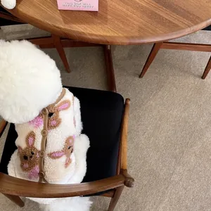 Nahaufnahme eines weißen Hundes, der eine kuschelige Fleece-Wärmeweste mit Hasen trägt