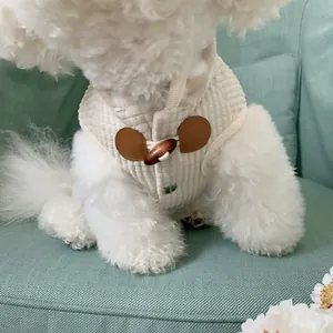 Close-up of a white quilted pet vest with wooden toggle buttons shown on a small dog.