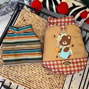 Close-up detail of dog winter harness vest with cute bear print and striped pet sweater