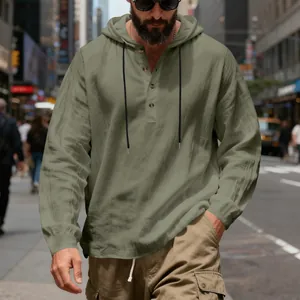 Detail view of men's olive green linen hoodie with buttoned Henley collar on street.