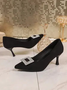 Nahaufnahme eleganter schwarzer spitzer Kitten-Heels mit luxuriöser Strassschnalle