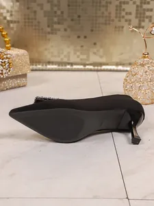 Detailansicht der schwarzen spitzen Stöckelschuhe mit eleganten Strassverzierungen.