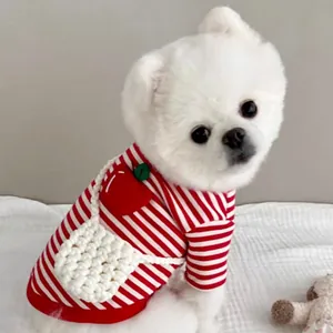 Detalle de un suéter de perro a rayas con diseño de fresa y pequeño bolso tejido