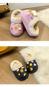 Gros plan de chaussons en peluche rose et noir avec breloques de dessins animés sur tapis