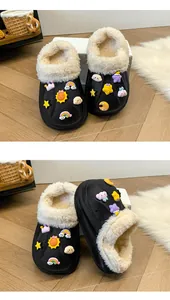 Détail de sabots noirs doublés de peluche avec breloques de dessin animé sur sol en bois.