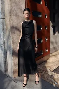 Sophisticated black satin sleeveless midi dress shown on a model in a stylish urban street