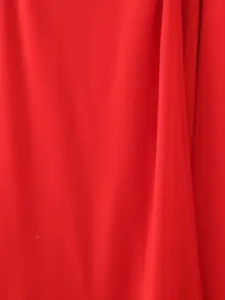Macro view of bright red silk satin fabric with elegant drapes and smooth texture