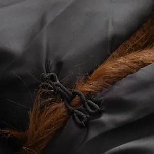 Macro detail van een winterjas met bruin imitatiebont en een zwarte koordsluiting.