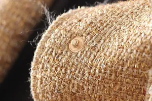 Close-up macro detail of textured tweed jacket featuring shimmering sequins and gold snap button