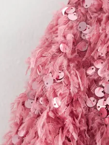 Nahaufnahme von pinkfarbenem Federfransenstoff mit schimmernden Pailletten auf einer Modejacke.