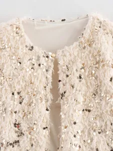 Detailaufnahme der flauschigen cremefarbenen Jacke mit glitzernden Goldpailletten