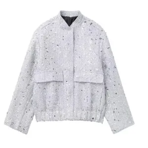 Detailed view of a grey sequined tweed jacket with front pockets and stand collar.