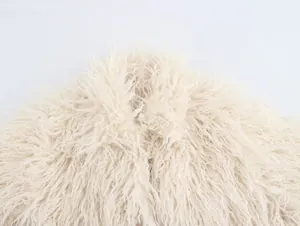 Detailed texture of a cream-colored faux fur plush jacket with long curly hair fibers