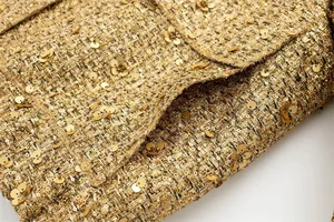 Macro view of gold sequined tweed fabric and pocket detail of a trendy women's jacket