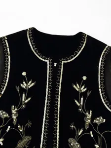 Detailopname van zwart fluwelen vest met ingewikkelde gouden bloemenborduurwerk en lovertjes