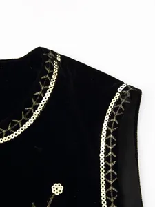 Detail van gouden lovertjes en sterborduurwerk op een elegant zwart fluwelen vest
