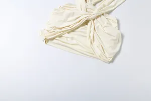 Detail view of pleated fabric texture and twisted design on a cream sleeveless dress