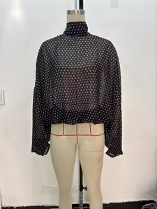 Detailansicht einer eleganten schwarzen gepunkteten Bluse auf einer Schneiderpuppe.